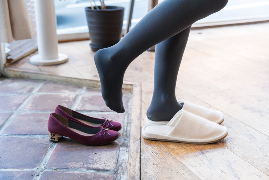 A woman who comes home and takes off her shoes and wears indoor slippers
